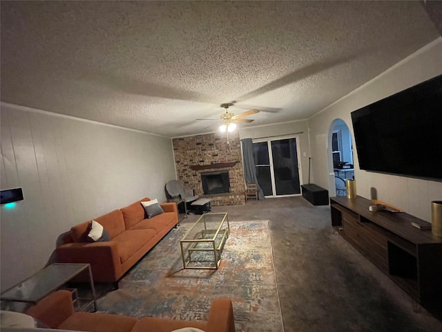 living room with a textured ceiling, ceiling fan, a brick fireplace, and wooden walls