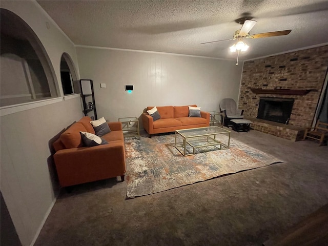 living room featuring crown molding, ceiling fan, carpet, a fireplace, and a textured ceiling