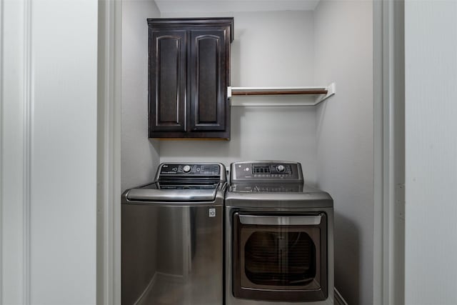 clothes washing area with washing machine and dryer and cabinets