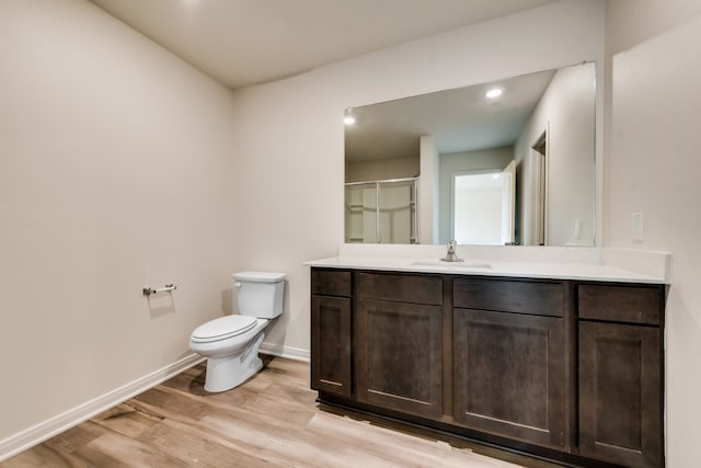 bathroom with a shower with shower door, hardwood / wood-style floors, toilet, and vanity