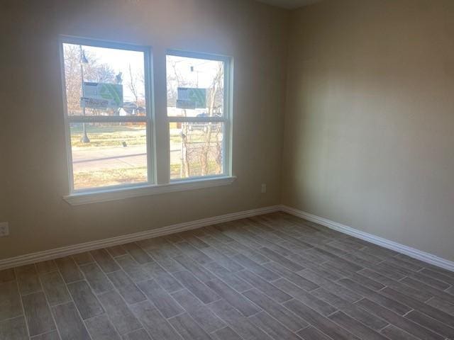 empty room featuring baseboards and dark wood finished floors