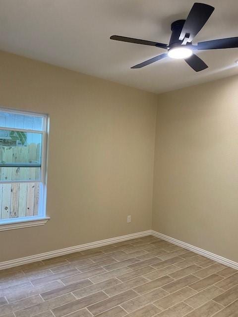 empty room featuring wood tiled floor, ceiling fan, and baseboards