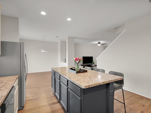 kitchen with pendant lighting, a center island, a kitchen bar, stainless steel appliances, and light wood-type flooring