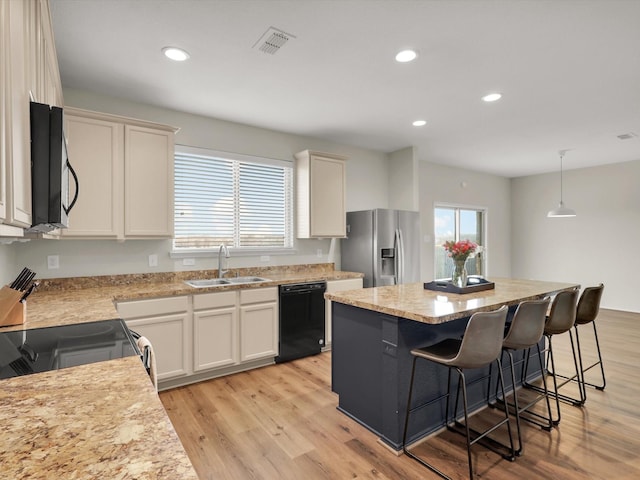 kitchen featuring a center island, sink, white cabinetry, hanging light fixtures, and appliances with stainless steel finishes