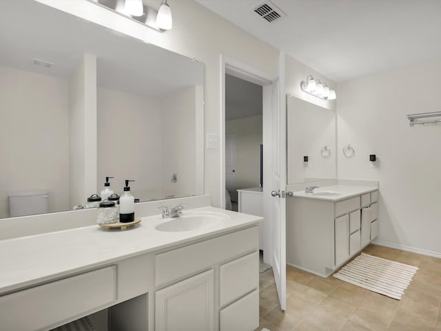 bathroom with toilet, vanity, and tile patterned flooring