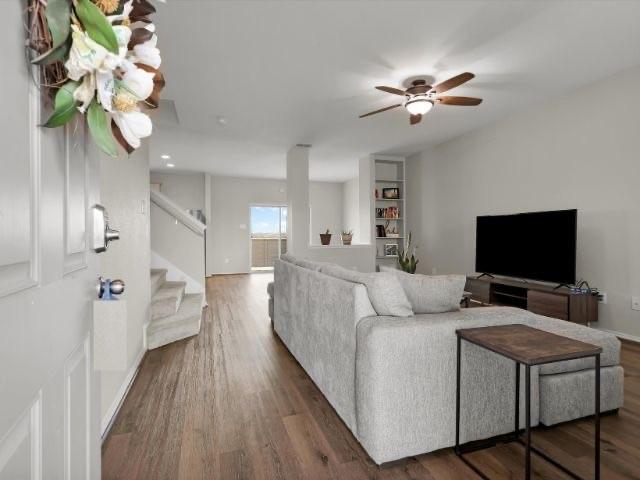 living room featuring ceiling fan and dark hardwood / wood-style flooring