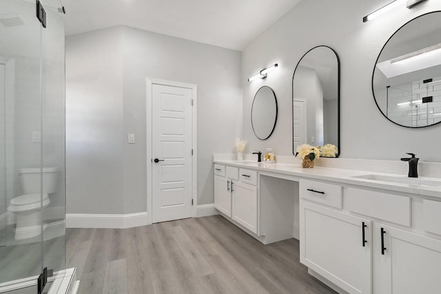 bathroom featuring toilet, a shower with door, hardwood / wood-style floors, and vanity