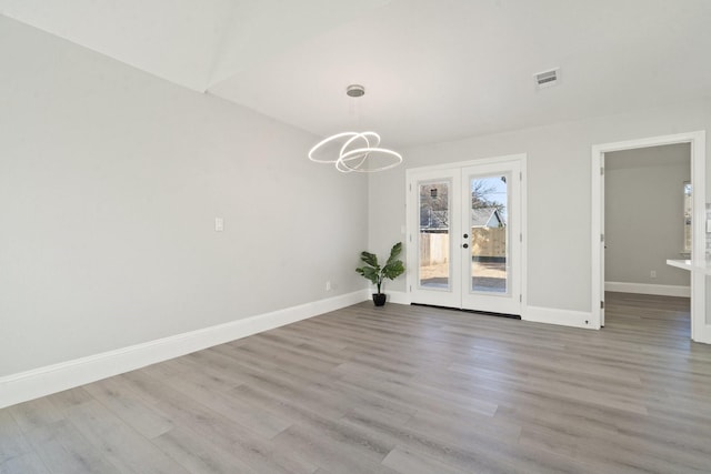 unfurnished dining area with light hardwood / wood-style floors, french doors, and a chandelier