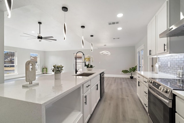 kitchen with white cabinets, electric range, wall chimney range hood, and a center island with sink