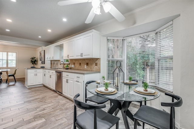 kitchen with ceiling fan, dishwasher, white cabinets, crown molding, and light hardwood / wood-style flooring