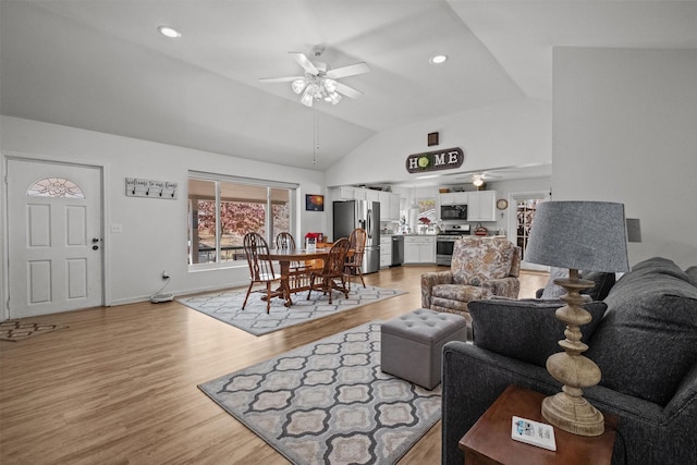 living room featuring ceiling fan, light wood-type flooring, and lofted ceiling