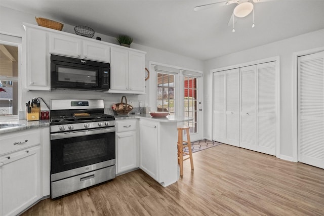 kitchen with stainless steel gas range, kitchen peninsula, light hardwood / wood-style flooring, and white cabinets