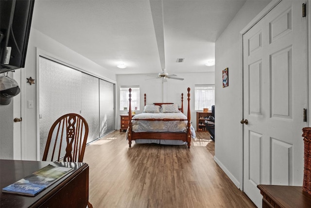 bedroom featuring ceiling fan, wood-type flooring, a closet, and multiple windows