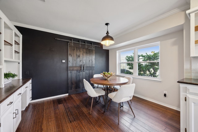 dining room featuring a barn door, dark hardwood / wood-style flooring, and ornamental molding