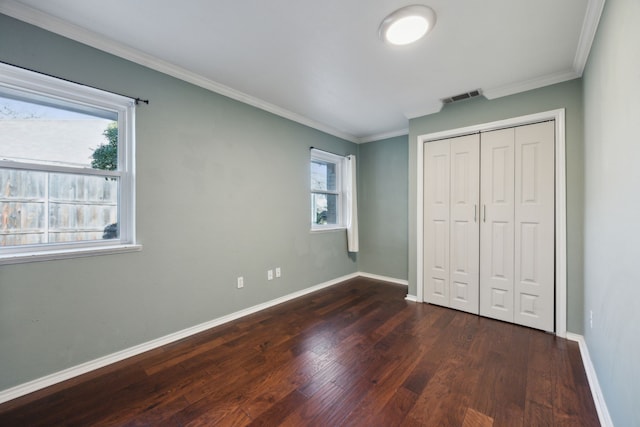 unfurnished bedroom with multiple windows, dark hardwood / wood-style floors, a closet, and ornamental molding