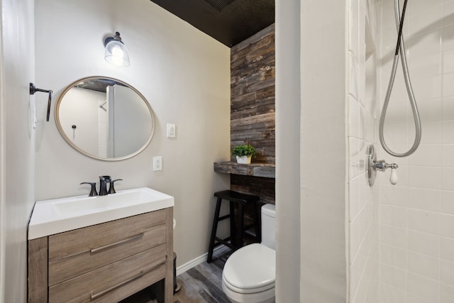 bathroom featuring wood-type flooring, toilet, walk in shower, and vanity