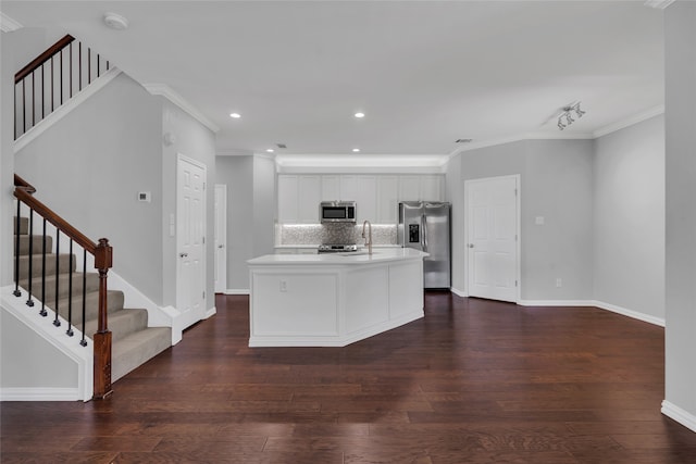 kitchen featuring a center island with sink, stainless steel appliances, backsplash, ornamental molding, and white cabinets