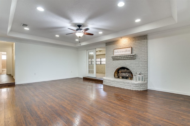 unfurnished living room with a textured ceiling, dark hardwood / wood-style flooring, a raised ceiling, ceiling fan, and a fireplace