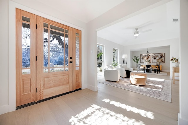 foyer featuring ceiling fan with notable chandelier and light hardwood / wood-style floors