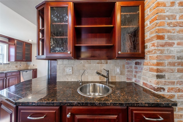 kitchen featuring stainless steel dishwasher, sink, dark stone countertops, and tasteful backsplash