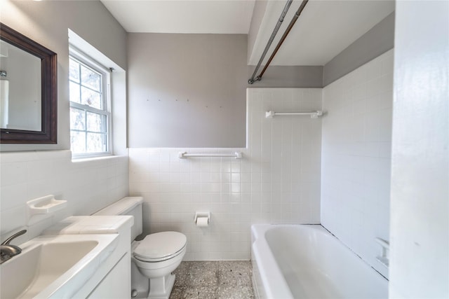 bathroom with toilet, vanity, and tile walls