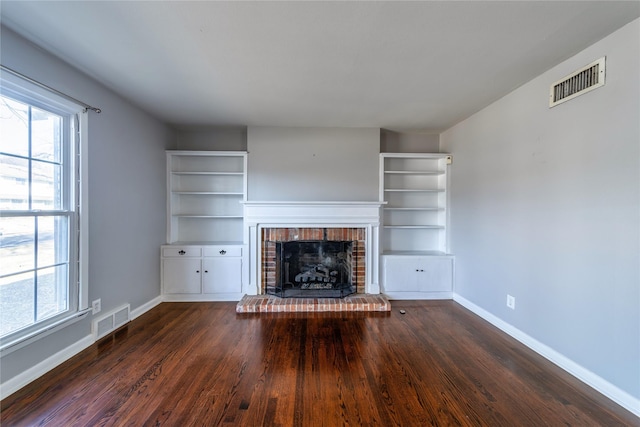 unfurnished living room with a brick fireplace and dark hardwood / wood-style floors