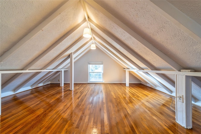 additional living space featuring vaulted ceiling, a textured ceiling, and hardwood / wood-style floors