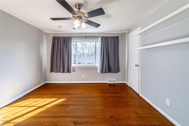 empty room with ceiling fan and dark hardwood / wood-style flooring