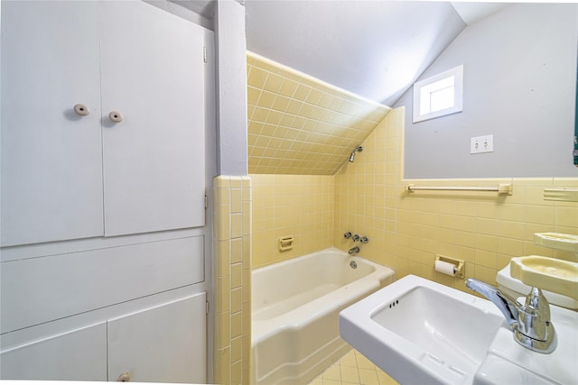 bathroom with vaulted ceiling, tile patterned flooring, tile walls, and sink