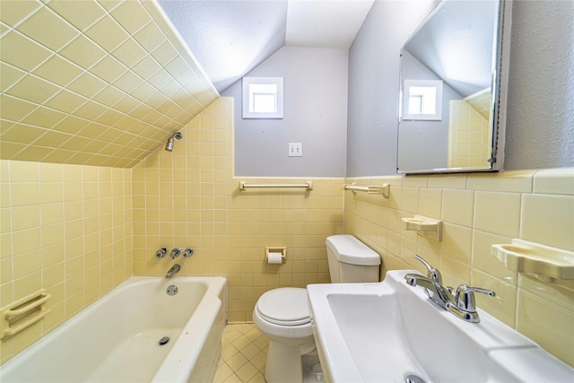 bathroom featuring a bathing tub, lofted ceiling, tile patterned floors, tile walls, and sink