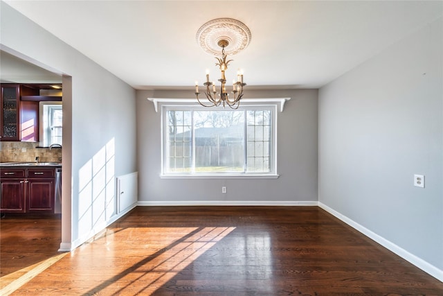 unfurnished dining area featuring sink, dark hardwood / wood-style floors, and a notable chandelier