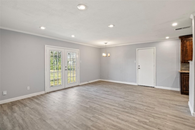 unfurnished living room featuring light hardwood / wood-style flooring, ornamental molding, french doors, and an inviting chandelier