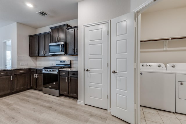 kitchen featuring stainless steel appliances, dark brown cabinetry, light stone counters, tasteful backsplash, and washing machine and clothes dryer