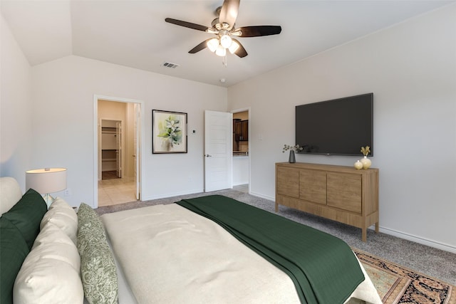 carpeted bedroom with vaulted ceiling, a walk in closet, and ceiling fan