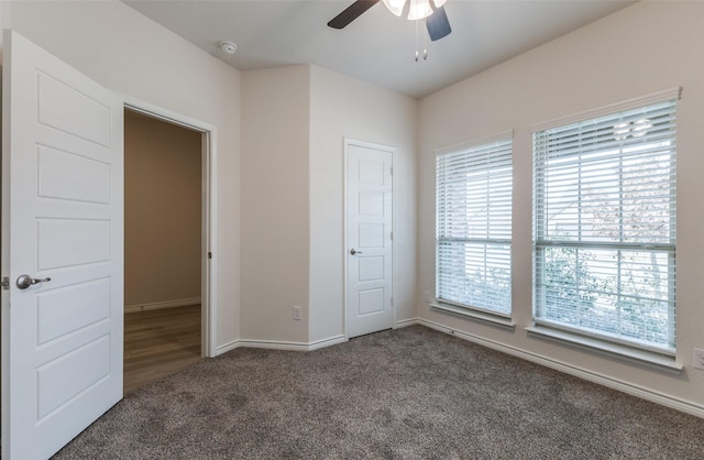 unfurnished bedroom with ceiling fan and dark carpet