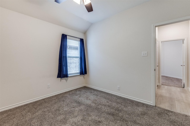 carpeted spare room with ceiling fan and vaulted ceiling