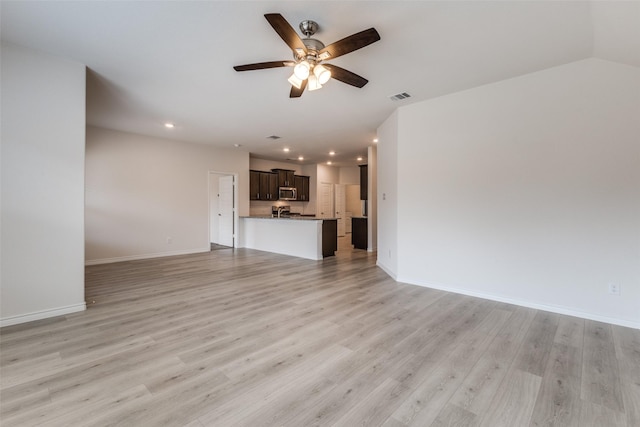 unfurnished living room featuring vaulted ceiling, ceiling fan, and light hardwood / wood-style flooring