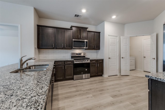 kitchen featuring light stone counters, sink, stainless steel appliances, and light wood-type flooring