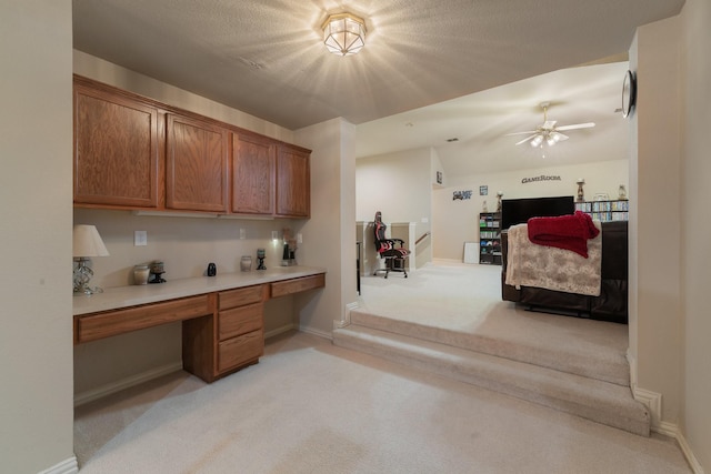 kitchen featuring light carpet, ceiling fan, and built in desk