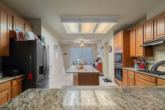 kitchen featuring black appliances, light tile patterned floors, decorative backsplash, and light stone counters