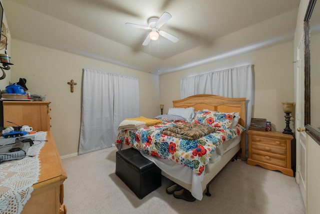 carpeted bedroom featuring ceiling fan and a raised ceiling