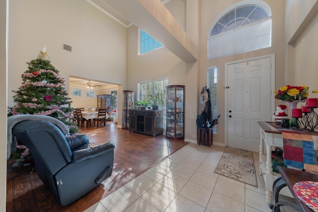 entrance foyer featuring ceiling fan, light tile patterned flooring, and a towering ceiling