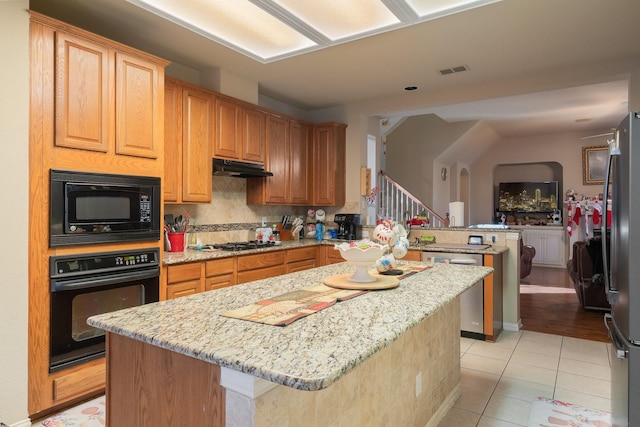 kitchen with light tile patterned floors, kitchen peninsula, decorative backsplash, a kitchen island, and black appliances