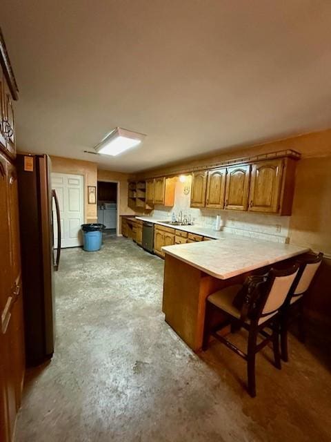 kitchen with sink, kitchen peninsula, appliances with stainless steel finishes, and a kitchen bar