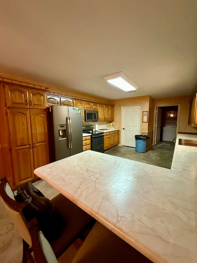 kitchen featuring washer / clothes dryer, a breakfast bar area, and stainless steel appliances