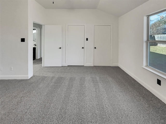 unfurnished bedroom with vaulted ceiling, carpet flooring, and multiple windows