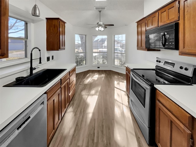 kitchen with pendant lighting, stainless steel appliances, plenty of natural light, sink, and light hardwood / wood-style flooring