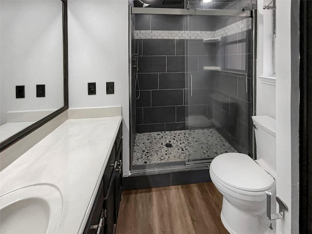 bathroom with a shower with shower door, hardwood / wood-style floors, toilet, and vanity