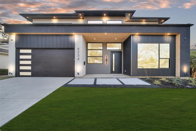 contemporary home featuring a garage and a lawn