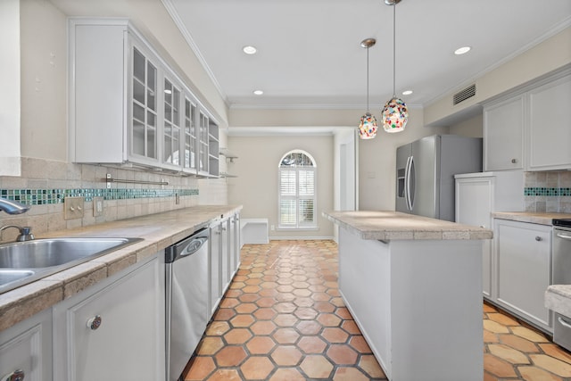 kitchen with pendant lighting, white cabinets, stainless steel appliances, decorative backsplash, and crown molding